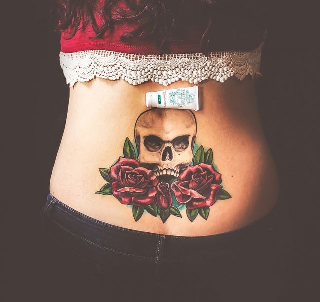 Tattoo balm on a woman's back tattooed with a skull and roses