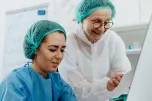 A Pair of Women Wearing Bouffant Caps and a White and Blue Surgical Gowns