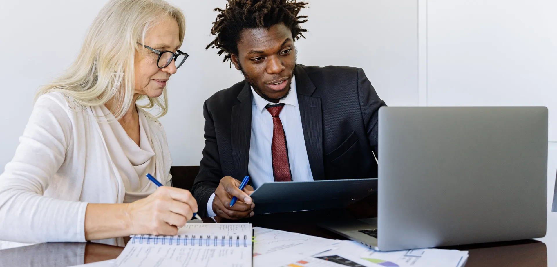 Elderly Woman Looking at the Computer Beside a Man in Black Suit
