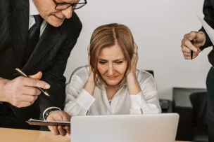 Man and Woman Sitting at Table Using Macbook