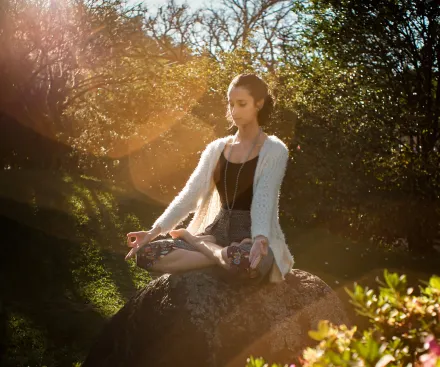 Woman Meditating on Rock
