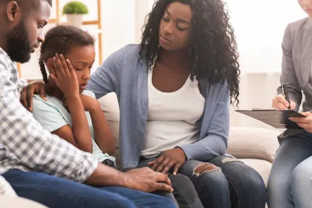 Photo of a Girl Looking at a Card with Her Parents