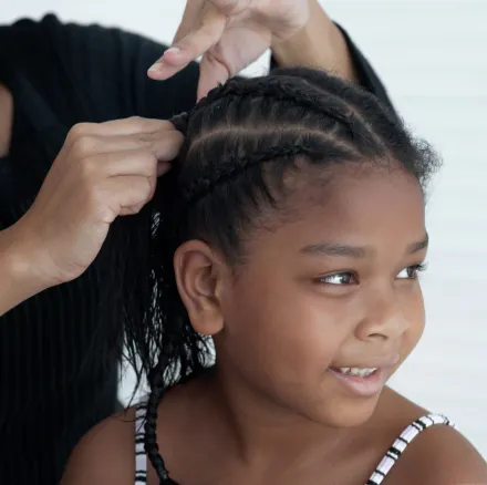 A young smiling child getting classic box braids