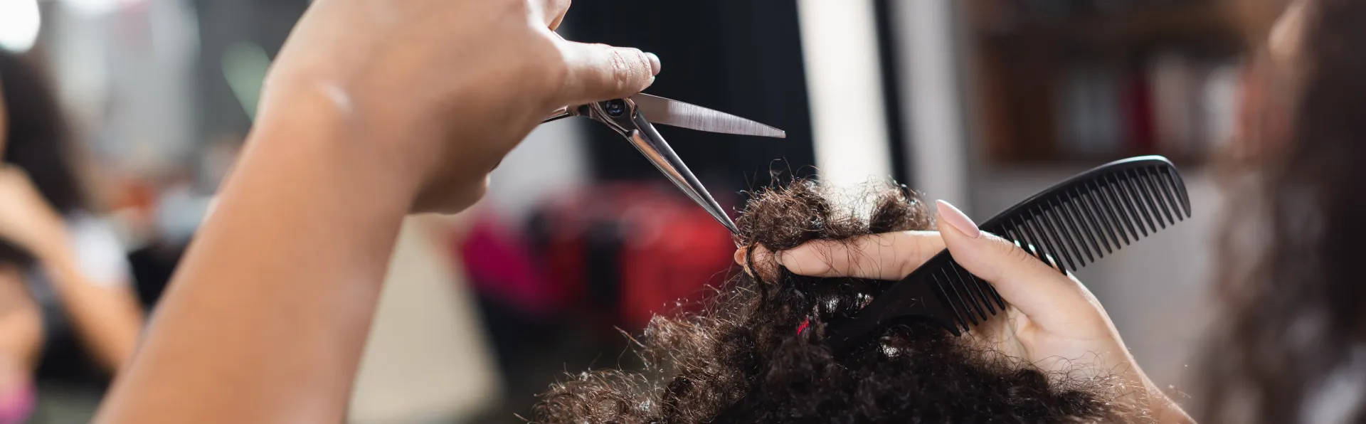 A close up of a woman's hands cutting natural hair