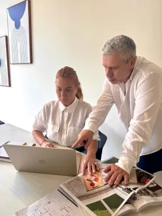 two white professionals working over a laptop and images