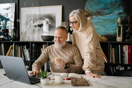 Elderly couple using a laptop at home, enjoying online activities and companionship.