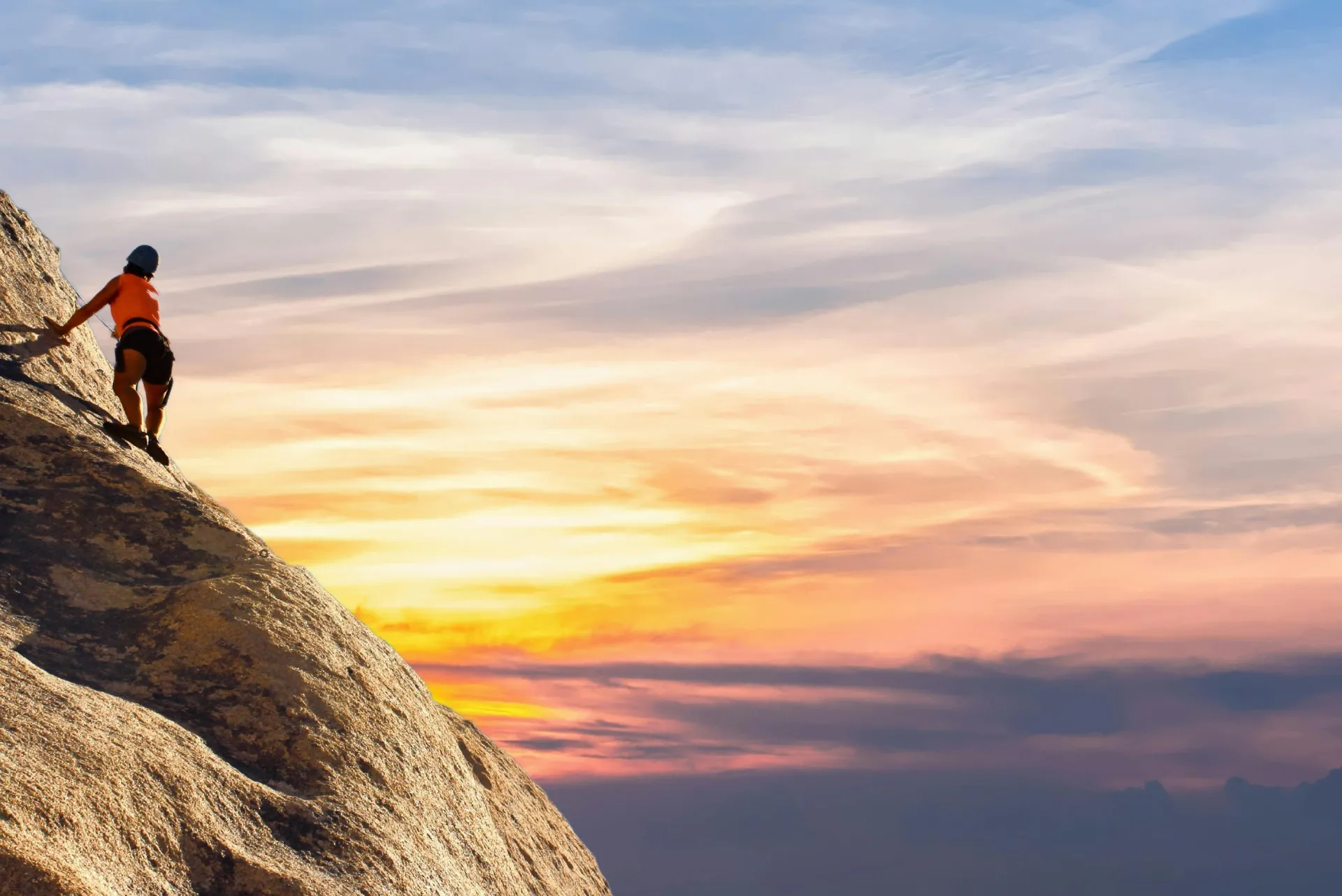 Climber conquers rock face at sunset, embracing the thrill and challenge.