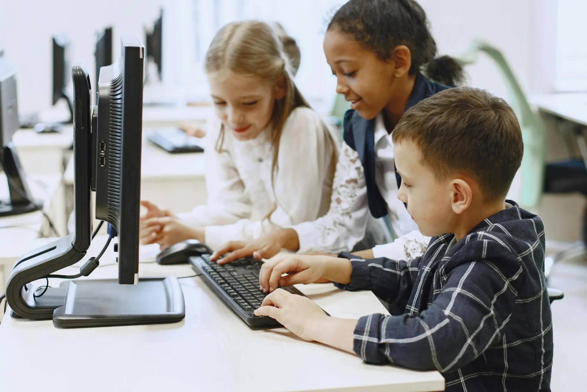 Children in a computer lab learning and collaborating on projects together.