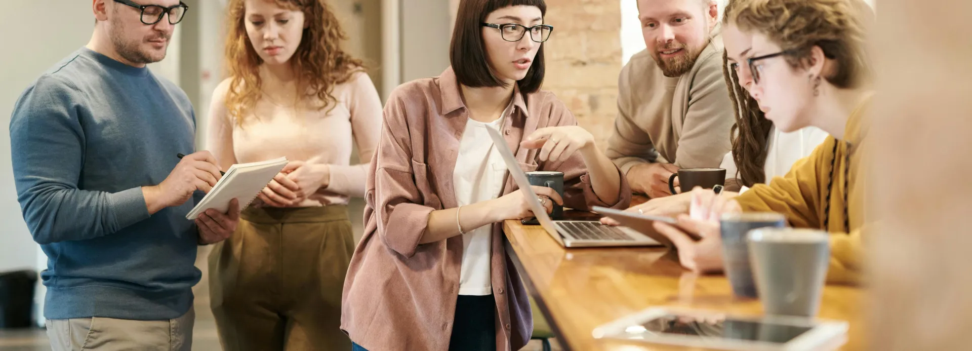 A diverse group of coworkers in a modern office engaged in teamwork using technology.