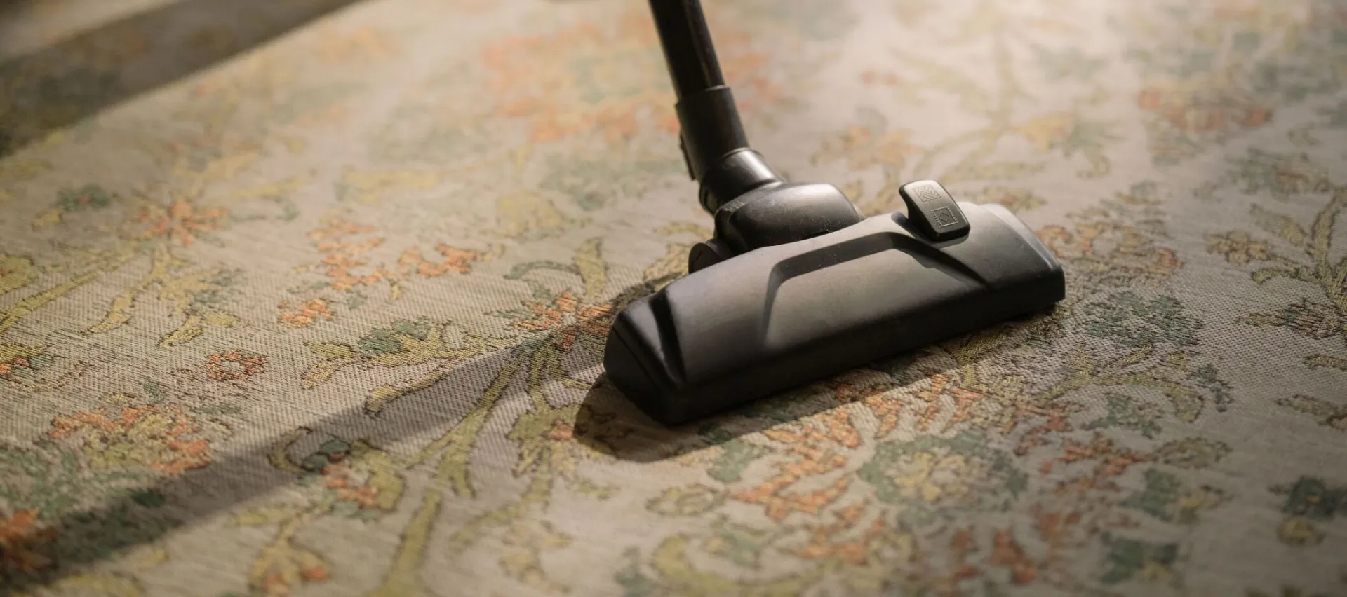 Close-up of a vacuum cleaner on a patterned carpet in a sunlit room, capturing a moment of household cleaning.