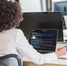 Back View of Woman Working on a Laptop in an Office
