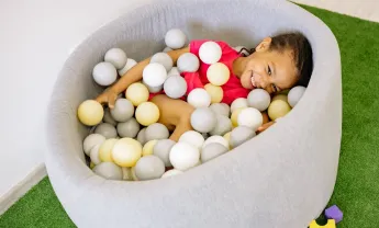 Girl With Braided Hair Playing Balls In A Tub