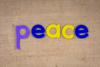 Vibrant letters spelling 'peace' on textured burlap surface.
