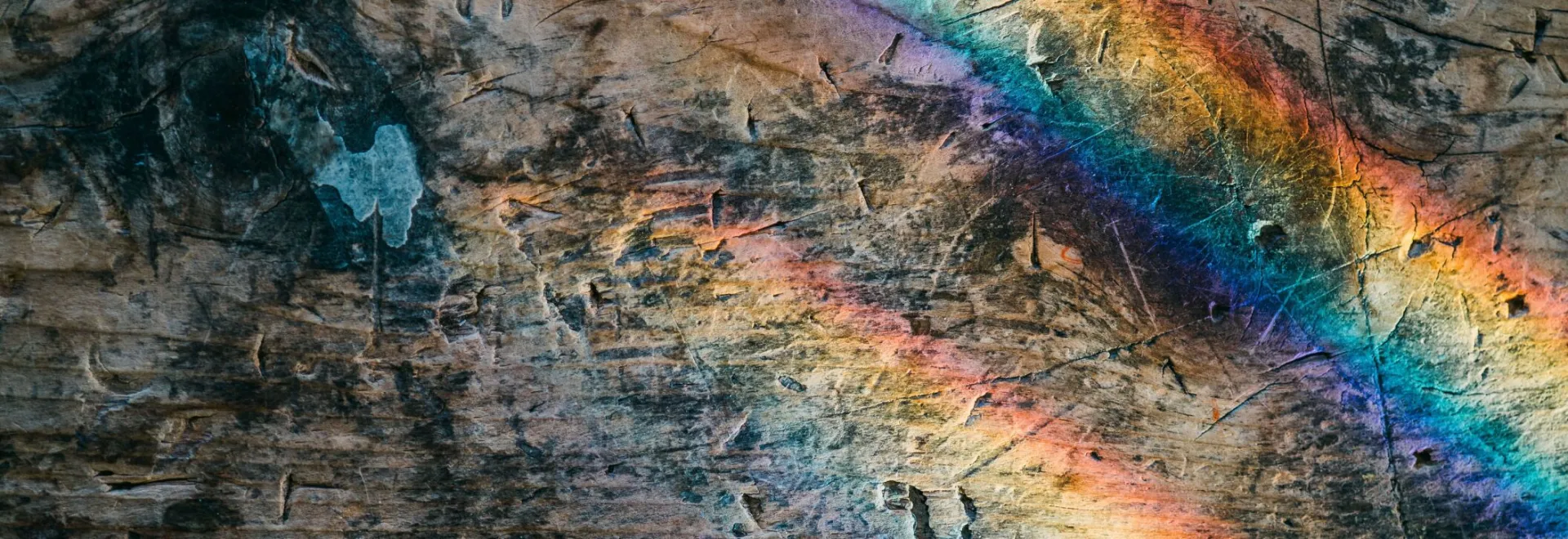 Vibrant rainbow reflections create a fascinating pattern on an aged wooden surface.
