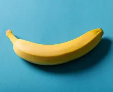 A fresh banana placed on a vibrant blue surface, showcasing minimalistic style.