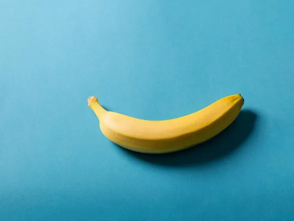 A fresh banana placed on a vibrant blue surface, showcasing minimalistic style.