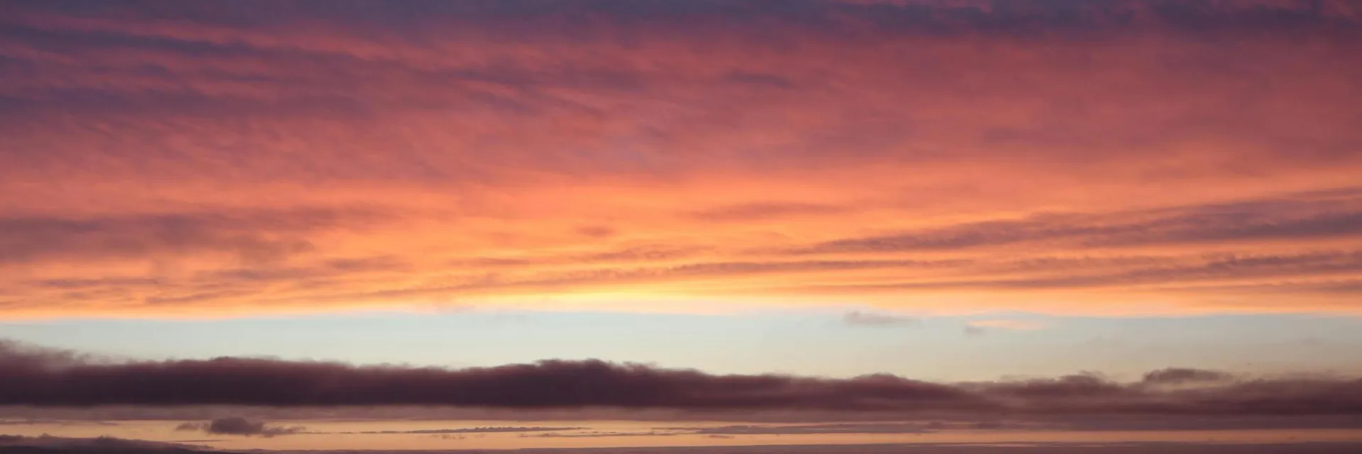 A serene ocean view at sunset with vibrant, colorful skies and gentle waves.