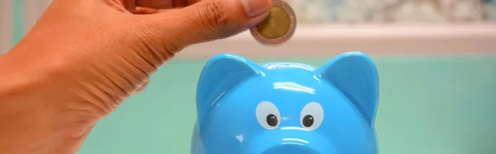 Person Putting Coin in a Piggy Bank