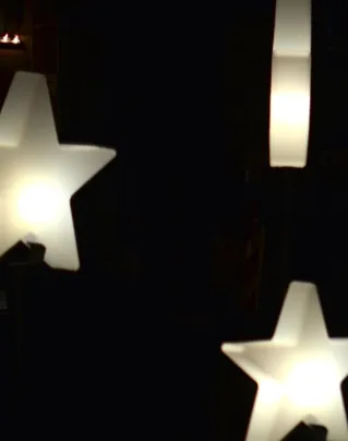 Creative star shaped garlands with glowing lamps decorating street against dark night sky