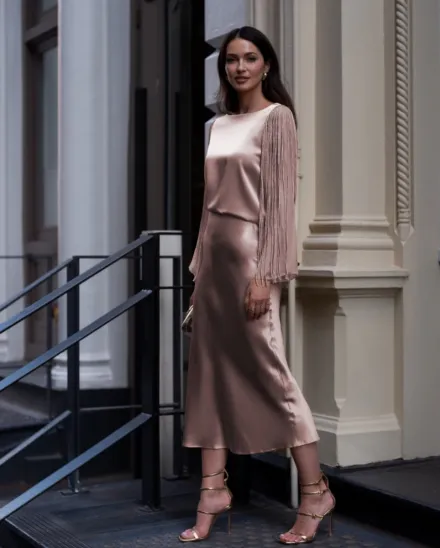 Lady standing in a white dress with silver jewelry and beige strappy heels
