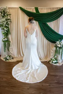 The back of a simple, sleek bridal gown with plunging v-back and sweep train