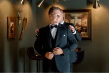Man adjusting elegant black tuxedo, perfect for formal occasions and style statement.