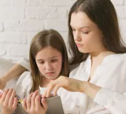 A Kid and Her Mother Reading a Book Tgoeteher