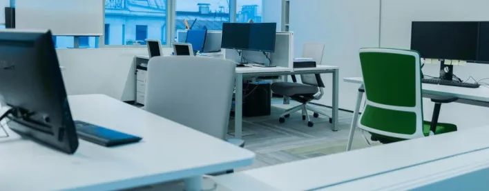 Bright and modern office environment with computer workstations and large windows.