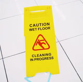 From above of plastic yellow sign with inscription Caution wet floor placed on clean white tiles
