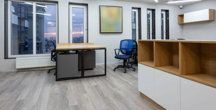 Interior of office with contemporary new wooden tables and chairs glowing by ceiling lamps