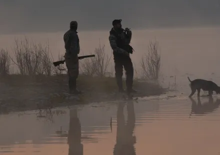 Two People with a Dog by a Lake