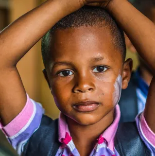 A young boy with contemplative expression indoors, emphasizing childhood and innocence.