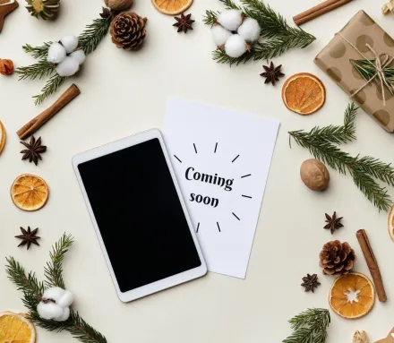 Flatlay featuring holiday decorations with gifts, spices, and a tablet on a light background.
