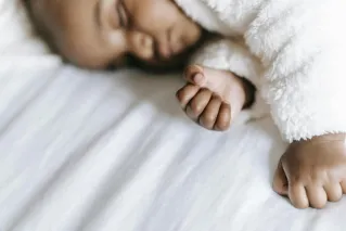Close-up of a serene baby sleeping peacefully with a soft focus on their gentle hands.