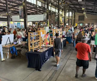 Tables and many people inside the shed area at Detroit Bookfest