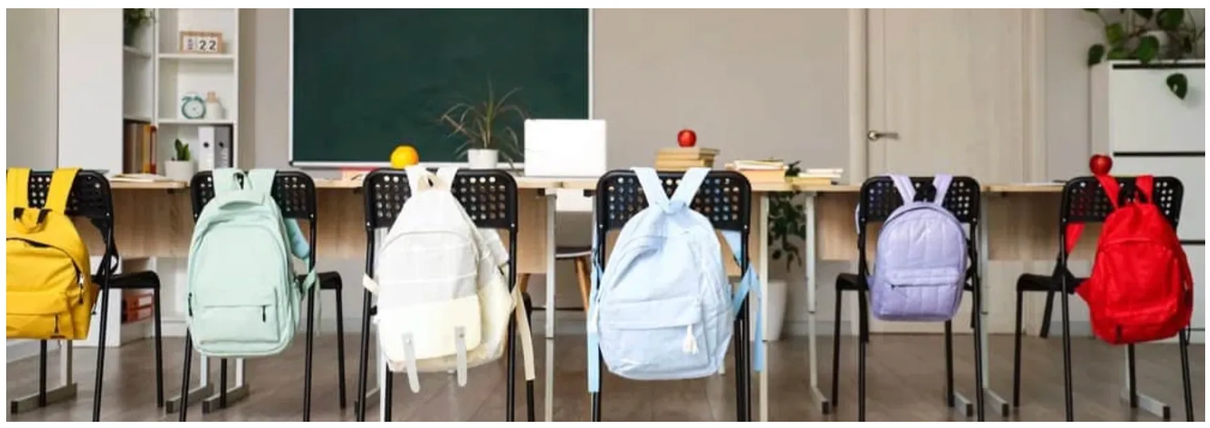 Backpacks hanging on the back of school chairs at desks