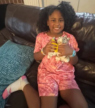 Young girl smiling and holding her raffle prizes, the lark and rabbit stuffie