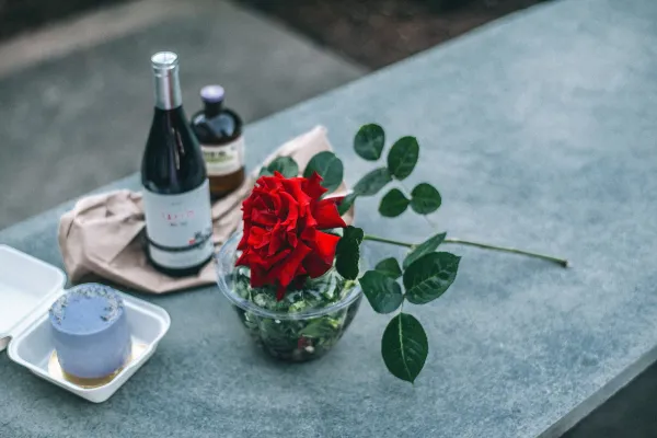 Composition of red rose placed on parapet near champagne bottle