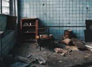 Old house with damaged furniture near weathered wall