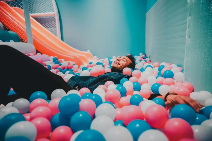 A man in a denim jacket enjoying a vibrant ball pit in Vancouver, Canada.