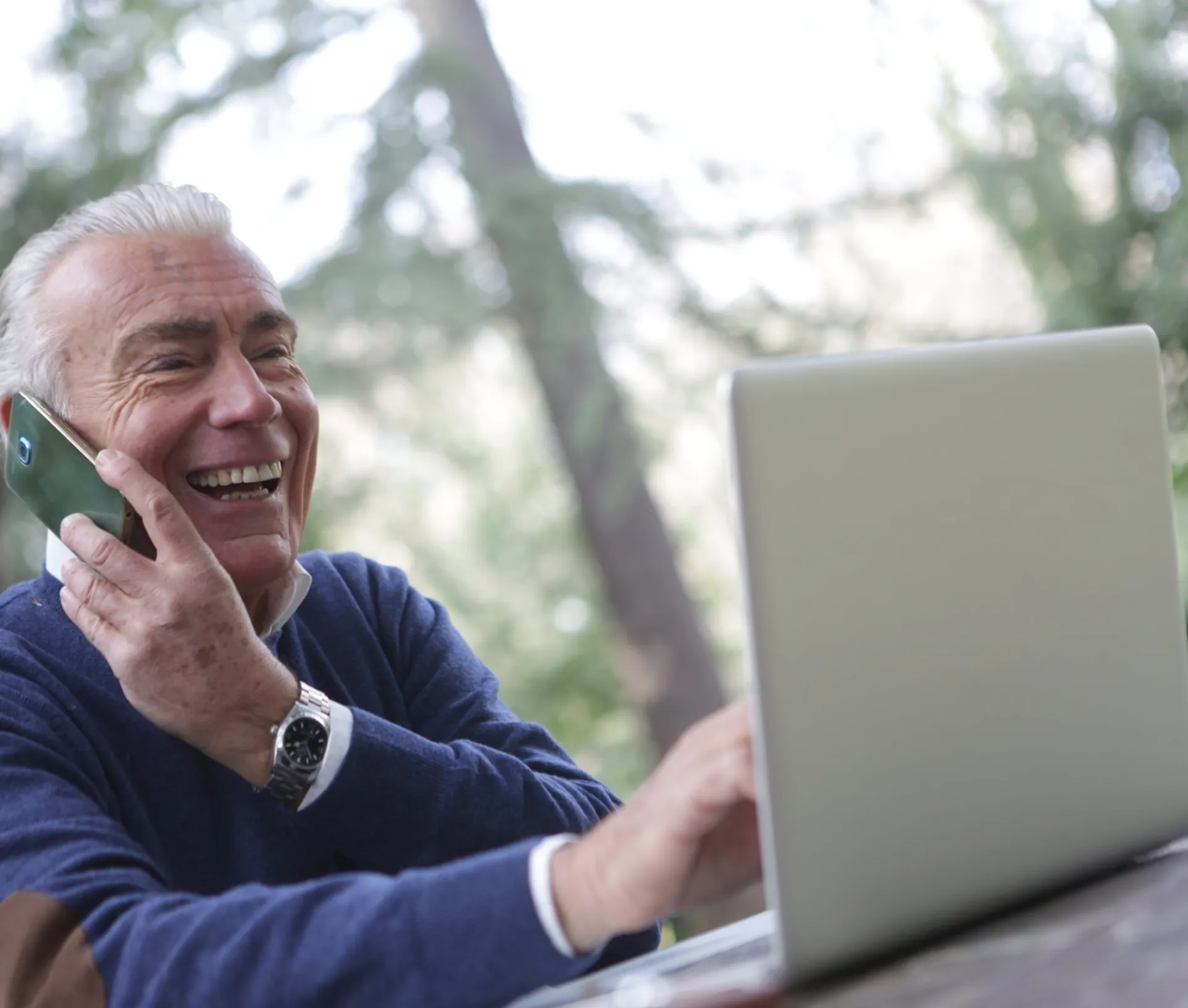 Man in Blue Long Sleeve Sweater Using Cellphone