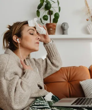 Woman Sitting on the Couch Wiping Her Sweat with Tissue