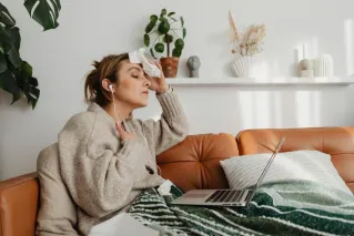 Woman Sitting on the Couch Wiping Her Sweat with Tissue