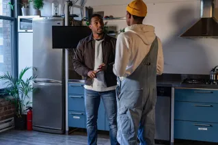 Two friends engaging in a casual conversation in a stylish kitchen.