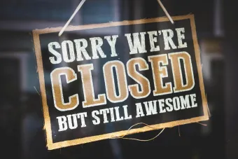 A playful closed sign on a shop door reading 'Sorry We're Closed But Still Awesome'.