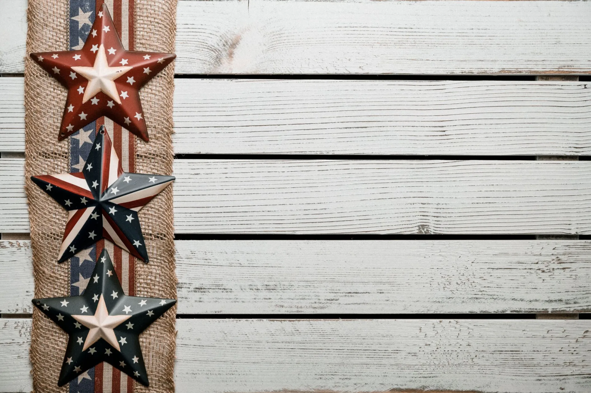 Patriotic stars and stripes decor on burlap against weathered wooden planks.
