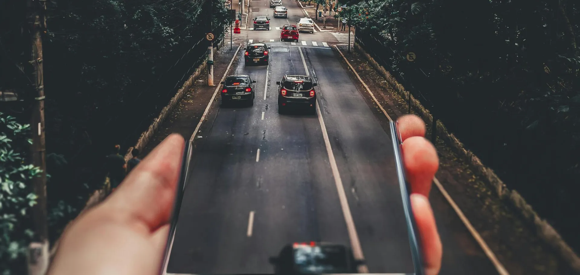 Forced Perspective Photography of Cars Running on Road Below Smartphone