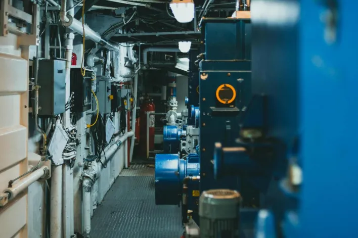A detailed view of industrial machinery and pipes in a maintenance corridor.