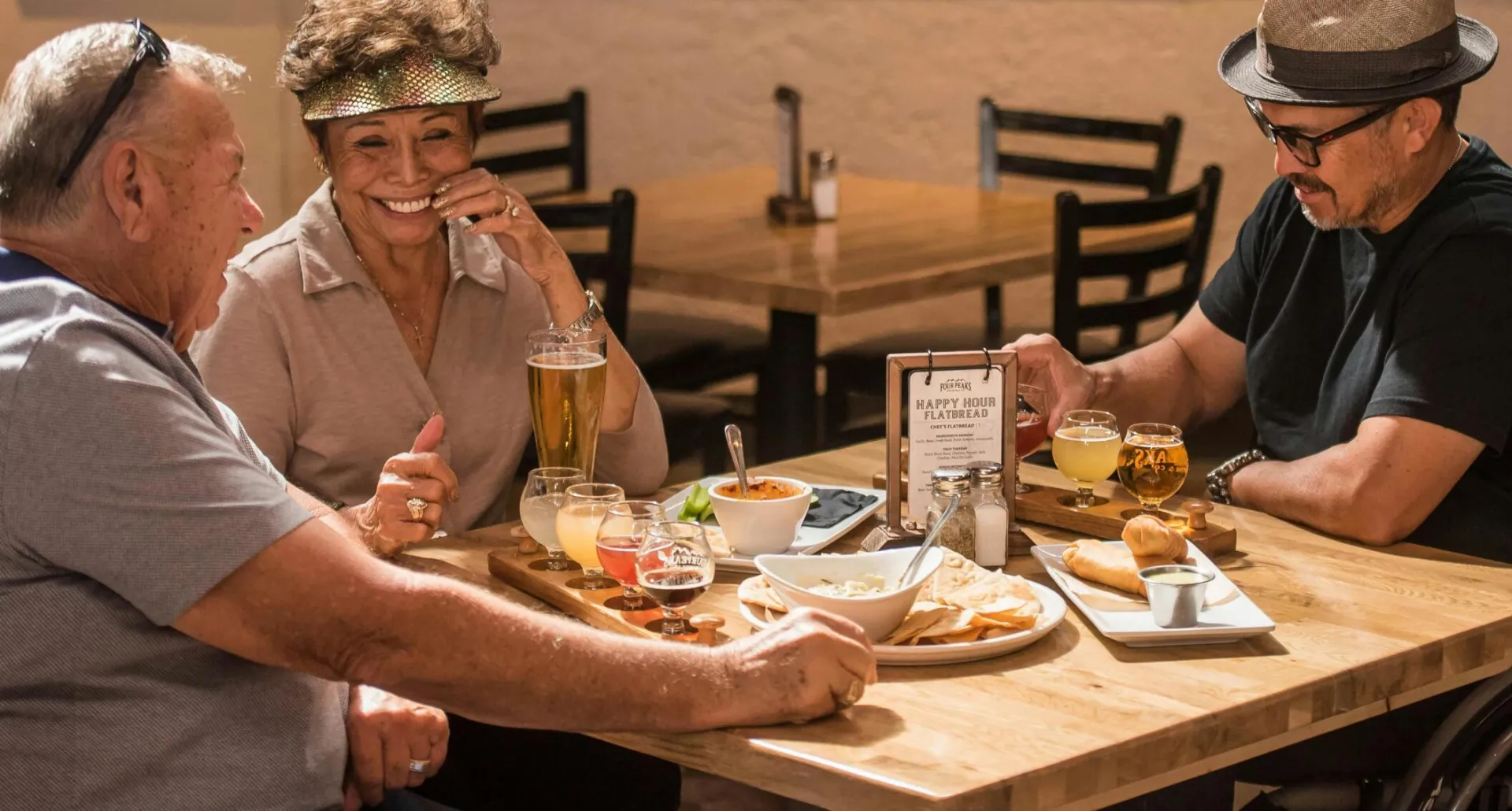 A lively group enjoying craft beer and snacks at an indoor restaurant setting.