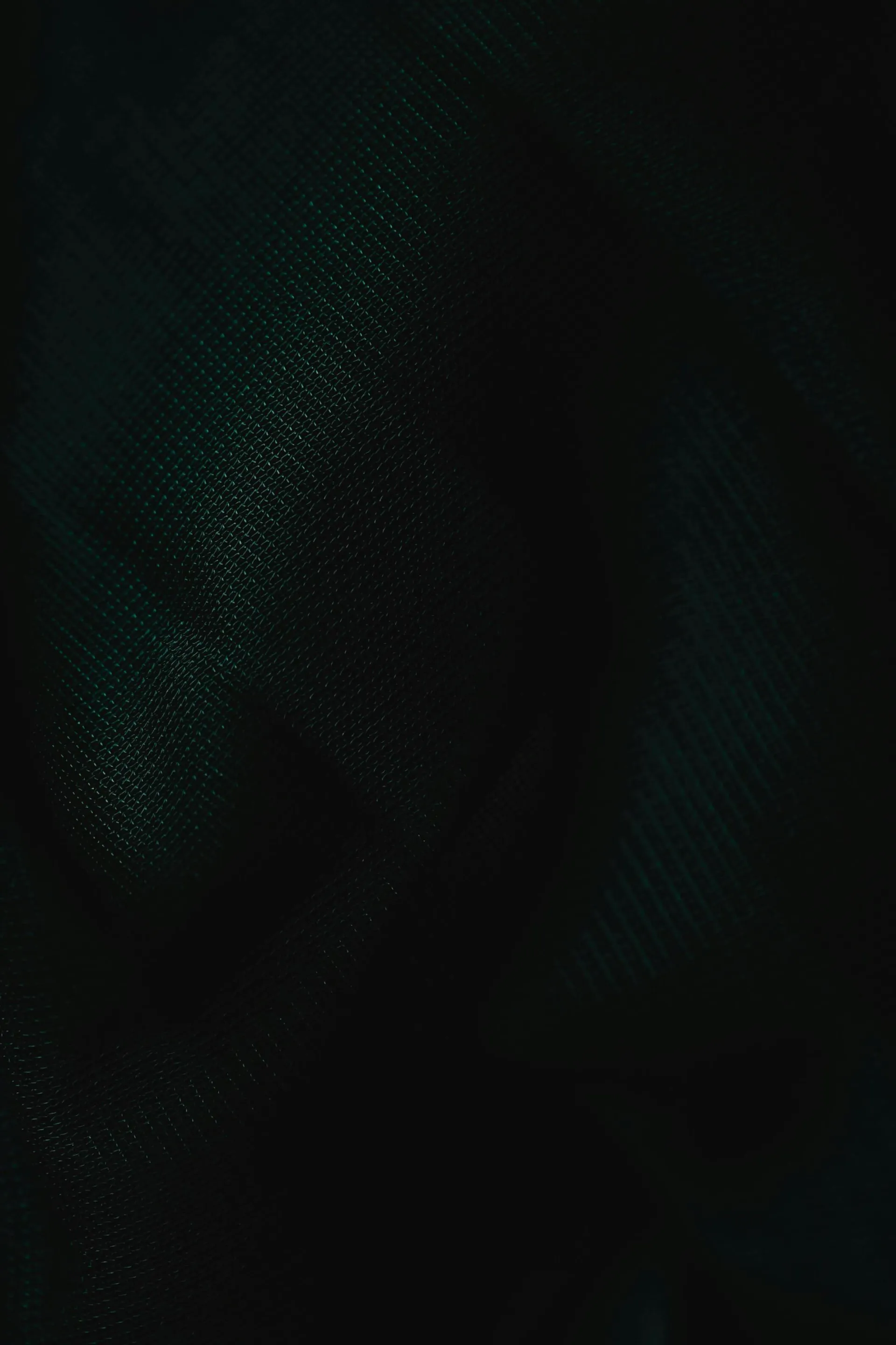 A dark fabric texture showcasing intricate patterns under subdued lighting.